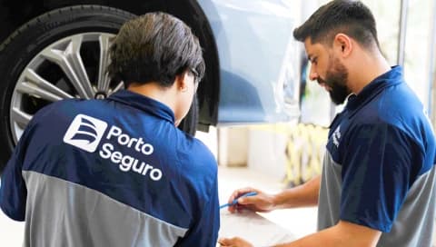 Especialistas da Porto, um homem e uma mulher, analisam juntos o serviço de um veículo no centro automotivo.