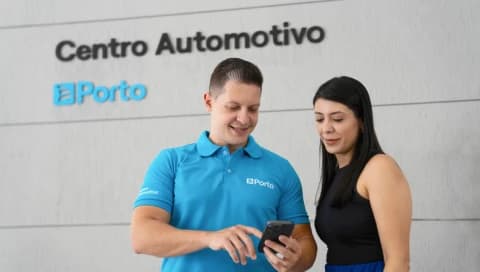 Especialista em um Centro Automotivo, mostra um detalhe no celular para uma cliente.